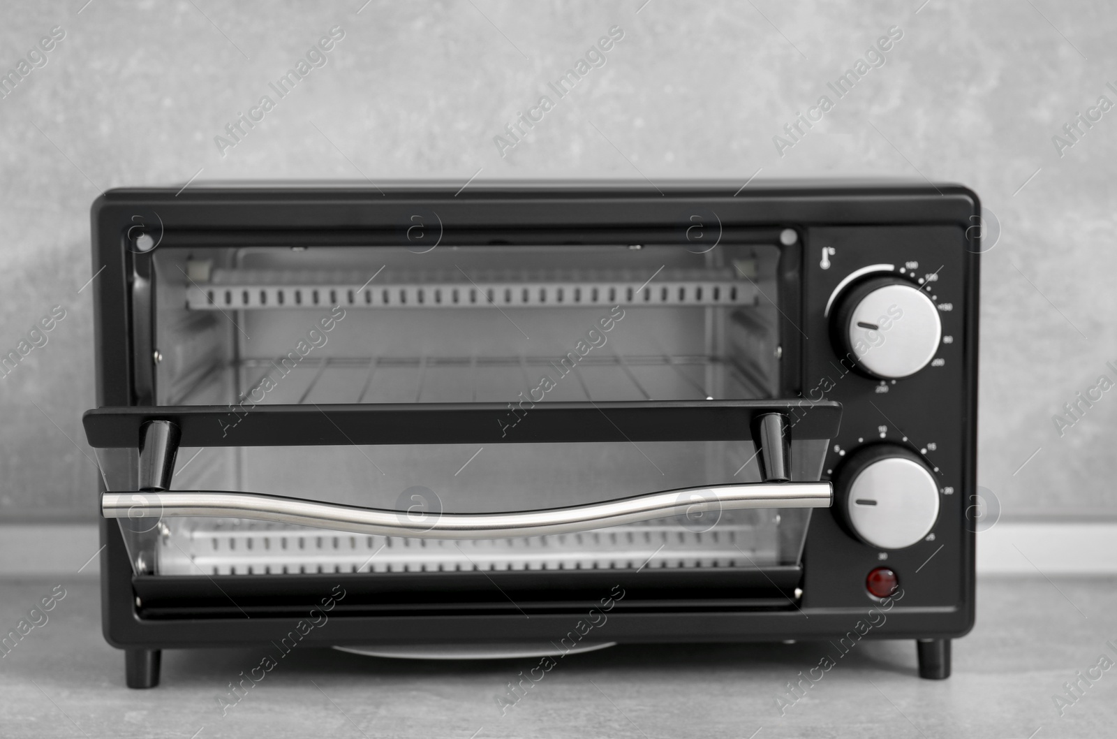 Photo of One electric oven on light grey table, closeup. Cooking appliance