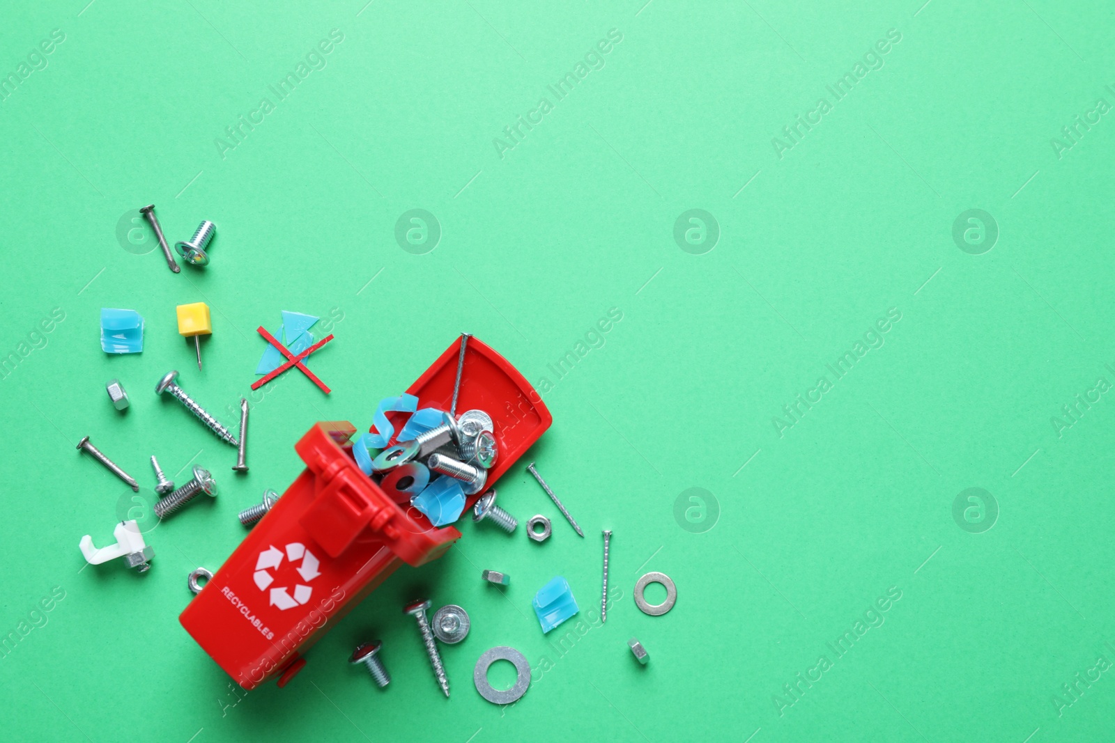 Photo of Mini recycling bin and different garbage on green background, flat lay. Space for text
