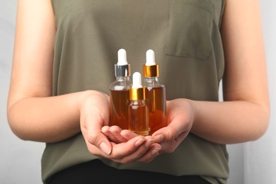 Photo of Woman holding bottles of essential oils, closeup