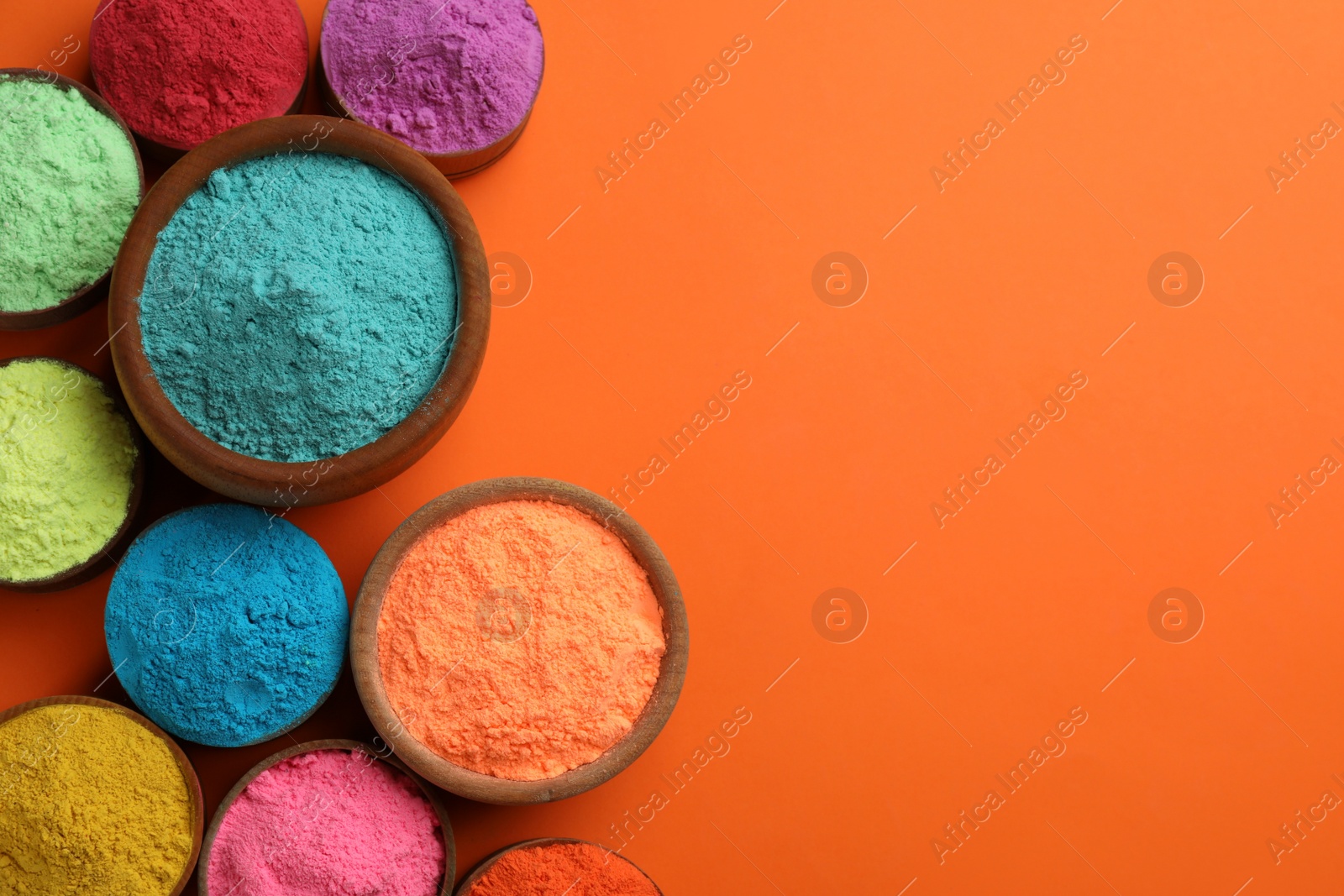 Photo of Colorful powders in bowls on orange background, flat lay with space for text. Holi festival celebration