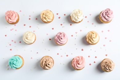 Photo of Flat lay composition with delicious birthday cupcakes on white background