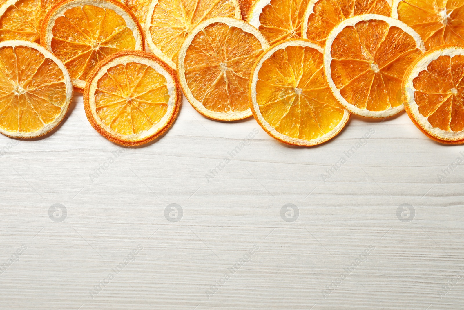 Photo of Dry orange slices on white wooden table, flat lay. Space for text