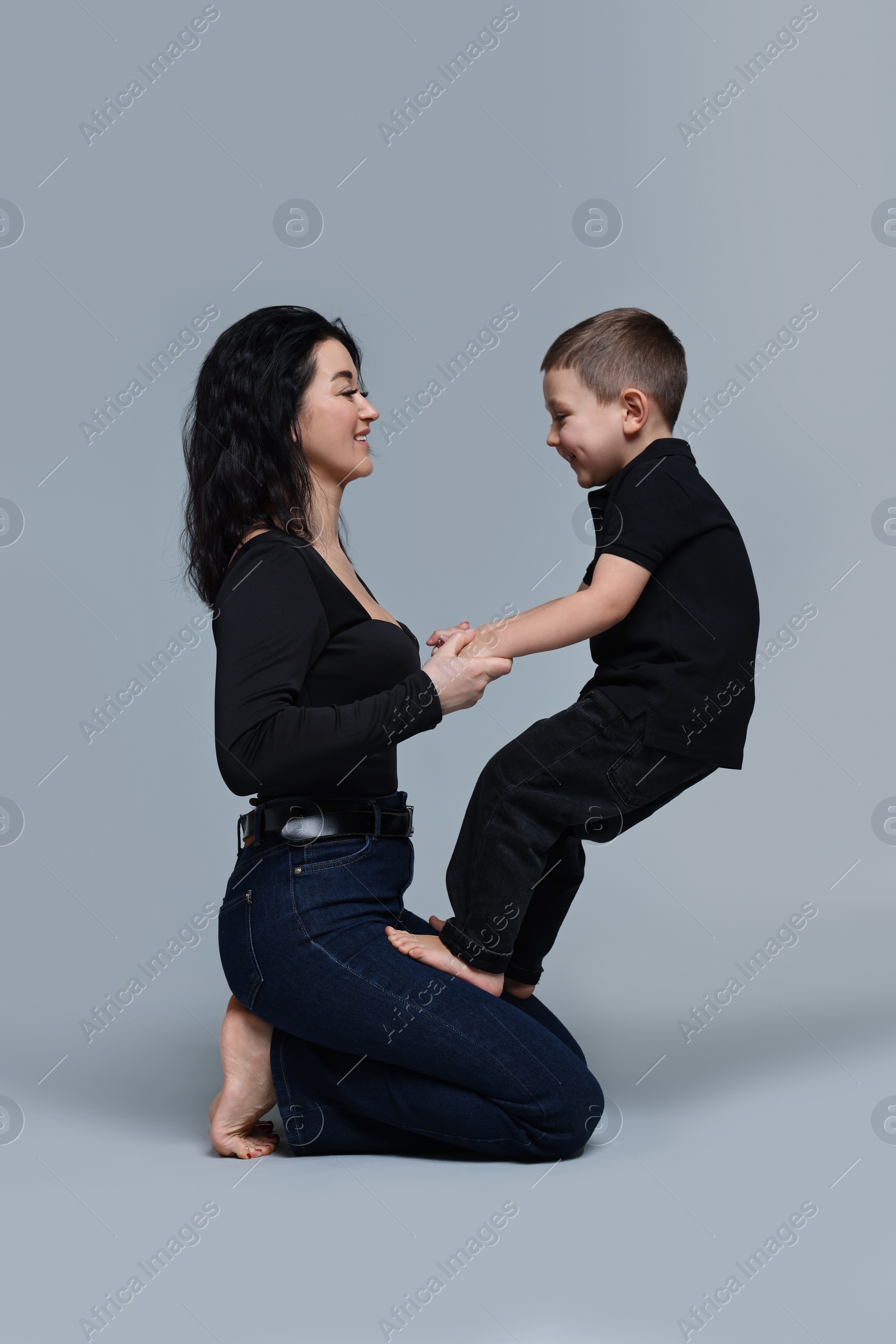 Photo of Beautiful mother with little son on grey background