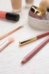 Photo of Lip pencils and other cosmetic products on white wooden table