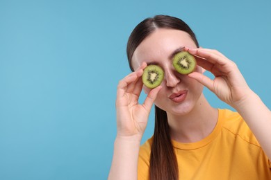 Photo of Woman covering eyes with halves of kiwi on light blue background, space for text