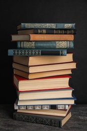 Stack of hardcover books on grey stone table against black background