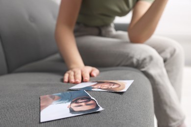 Photo of Woman sitting near torn photo on sofa indoors, focus on picture. Divorce concept