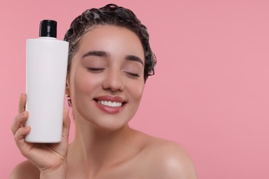 Photo of Washing hair. Portrait of beautiful happy woman with bottle on pink background. Space for text