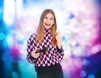 Photo of Teenage girl playing video games with controller on colorful background