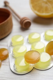 Many cough drops on white wooden table, closeup