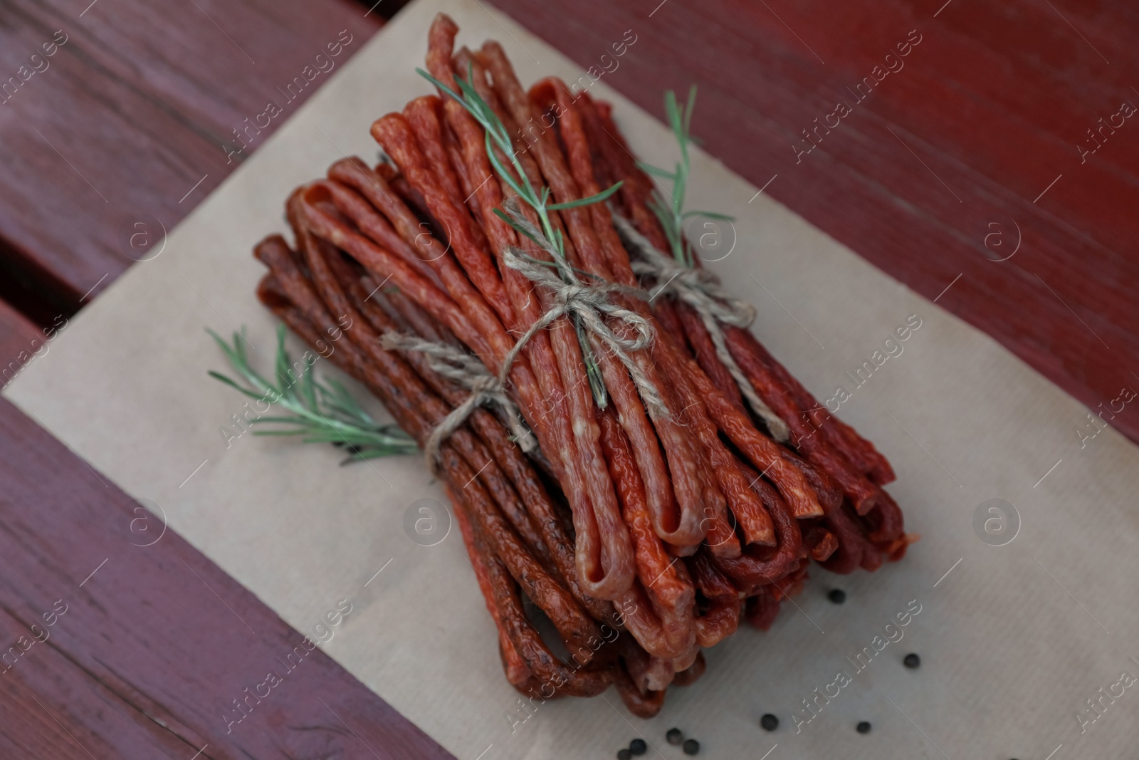 Photo of Tasty dry cured sausages (kabanosy) and spices on wooden table, above view