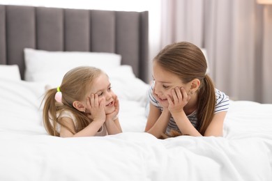 Photo of Cute little sisters on bed at home