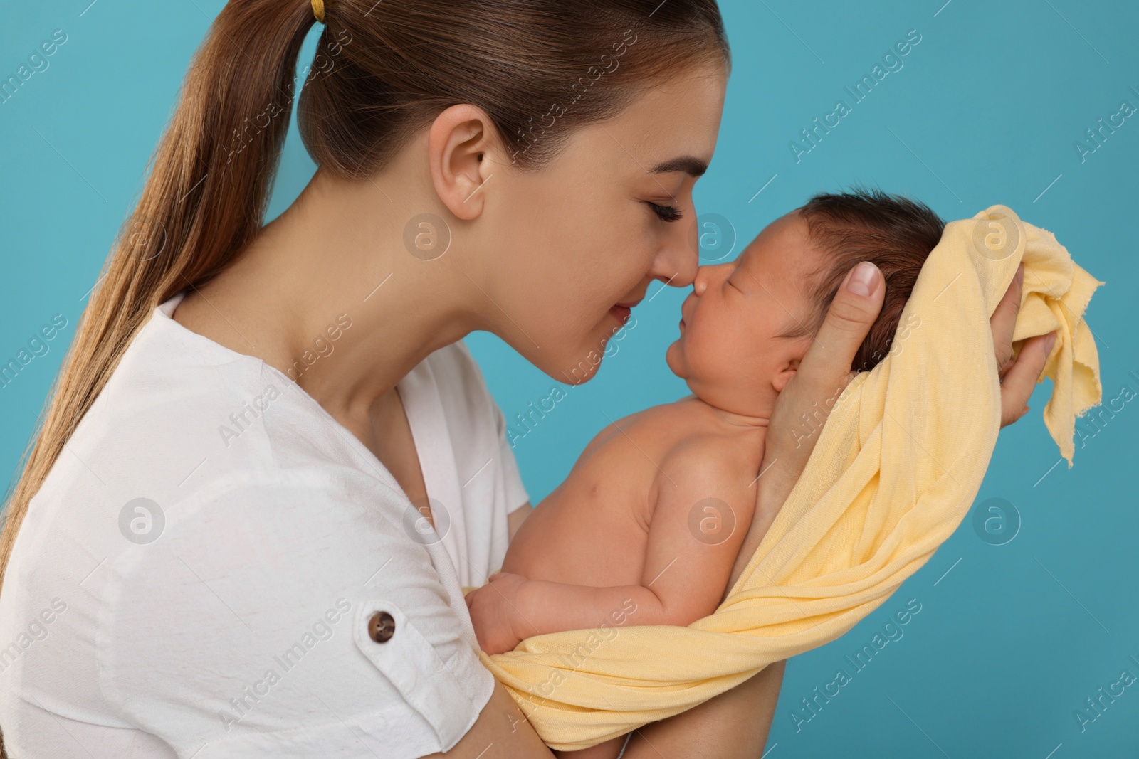 Photo of Mother with her cute newborn baby on light blue background
