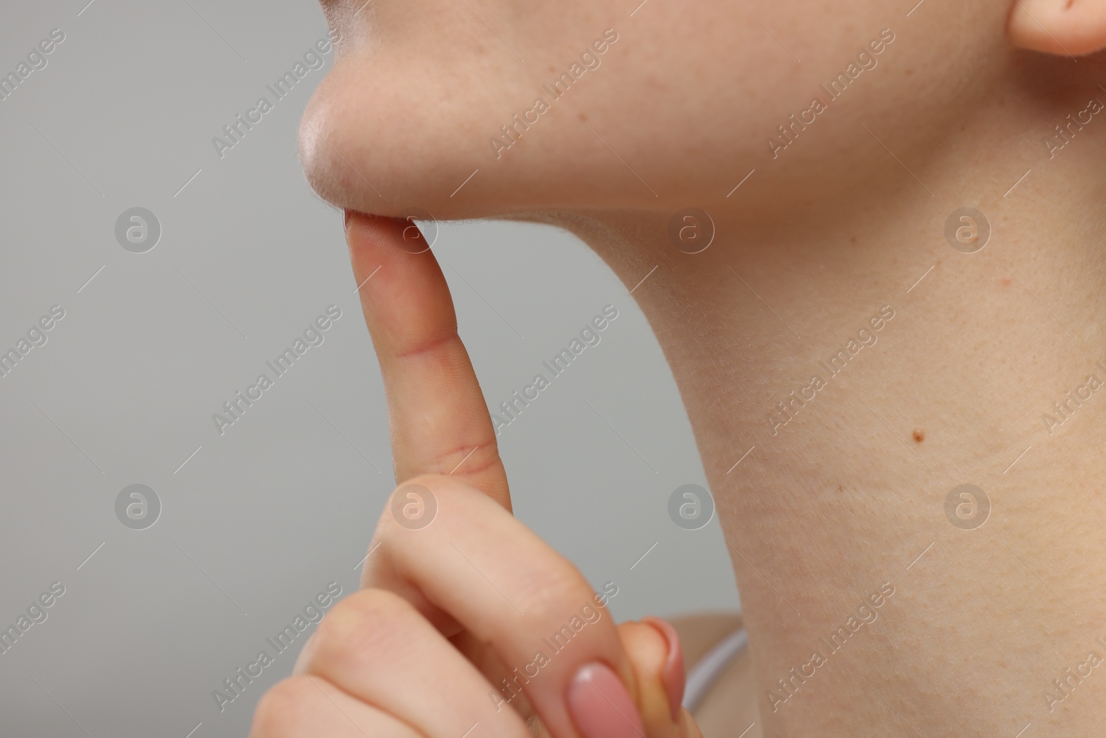 Photo of Woman touching her chin on grey background, closeup