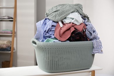 Photo of Laundry basket filled with clothes on table in bathroom