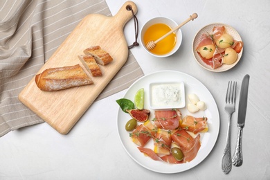 Photo of Flat lay composition with melon and prosciutto appetizer on light table