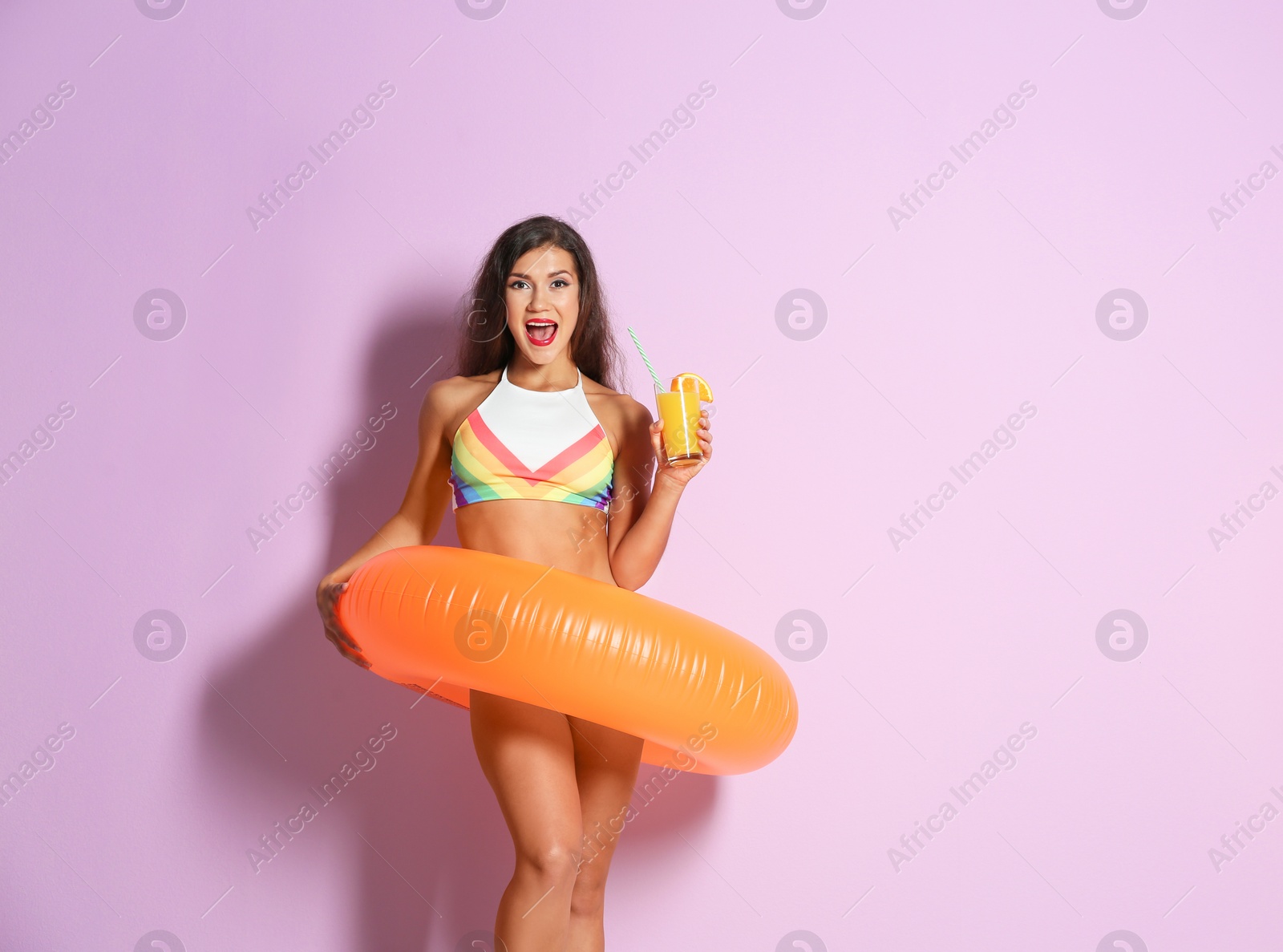 Photo of Beautiful young woman with inflatable ring and glass of cocktail on color background