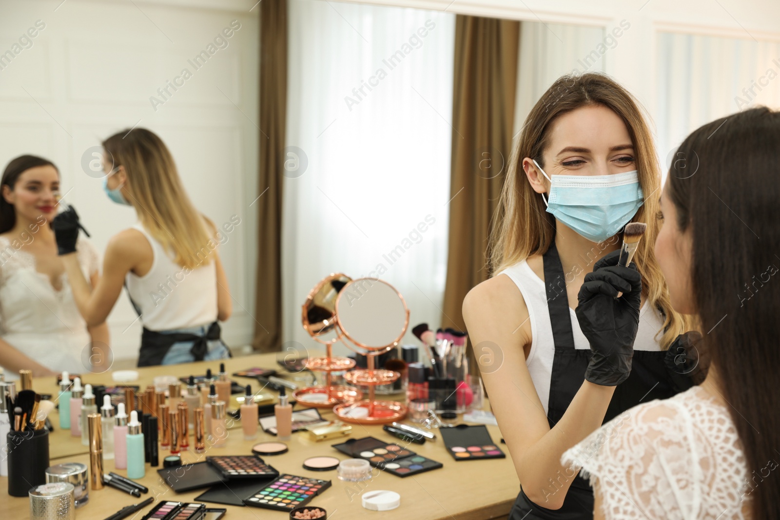 Photo of Professional makeup artist working with client in salon. Beauty services during Coronavirus quarantine