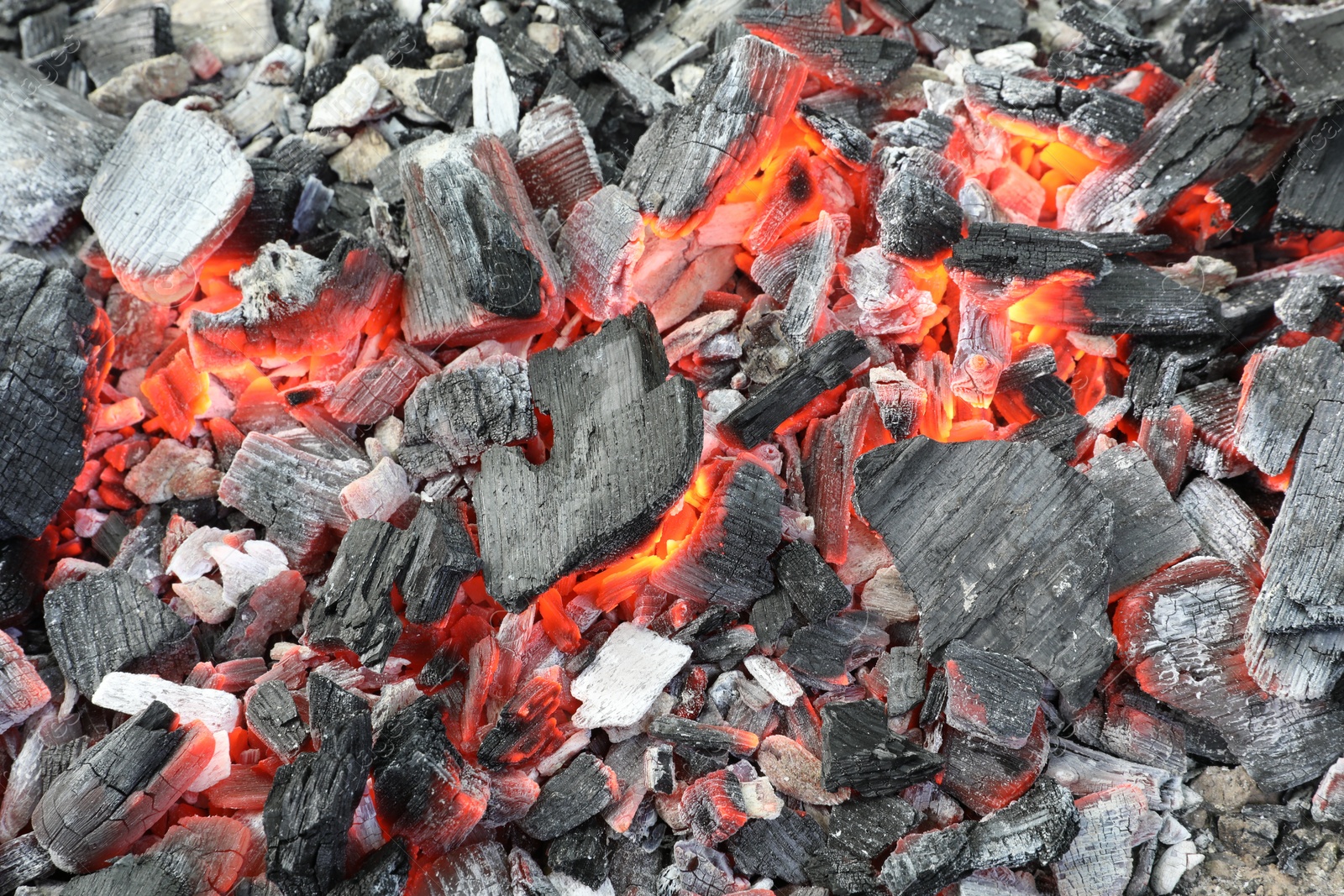 Photo of Many smoldering coals as background, closeup view