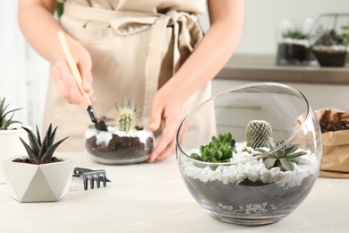 Glass florarium with different succulents and woman indoors