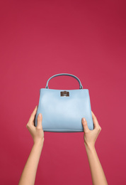 Photo of Woman holding stylish handbag on pink background, closeup