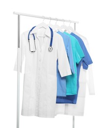 Photo of Doctor's gown with stethoscope and different medical uniforms on rack against white background