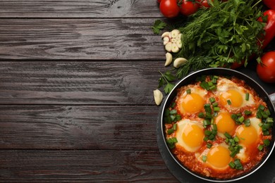 Photo of Flat lay composition with delicious shakshuka in frying pan on wooden table. Space for text
