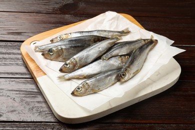 Photo of Fresh raw sprats on wooden table, closeup