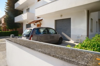 Modern apartment building with parked car in yard on sunny day