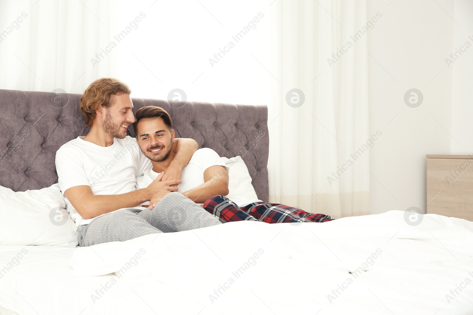 Photo of Happy gay couple on bed at home