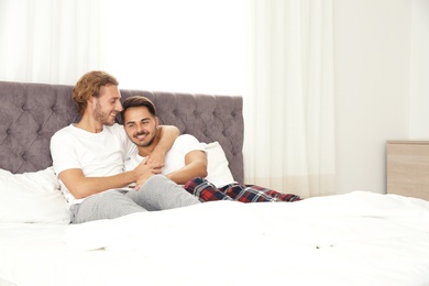 Happy gay couple on bed at home