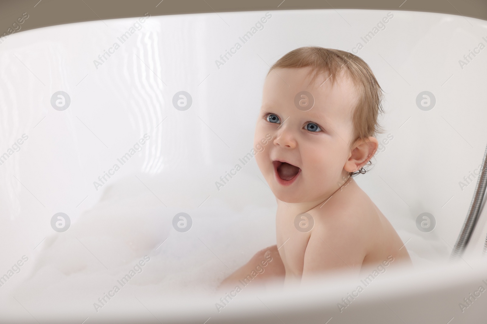 Photo of Cute little baby bathing in tub at home. Space for text