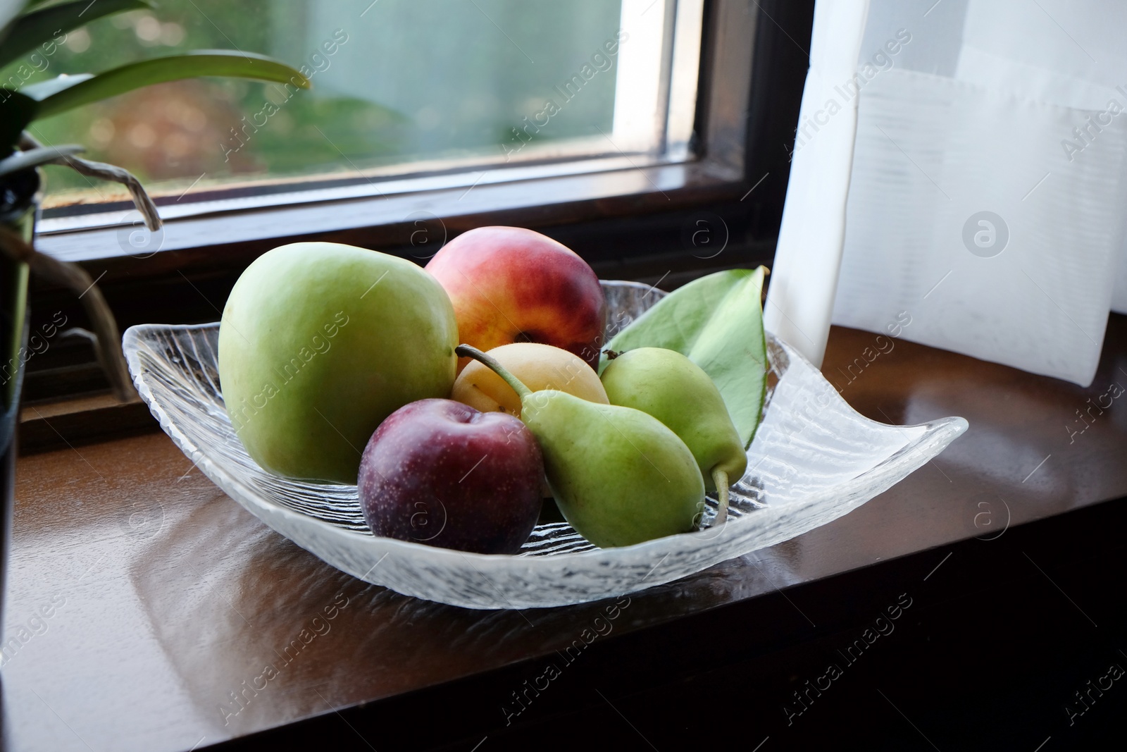 Photo of Juicy ripe fruits in vase on wooden window sill