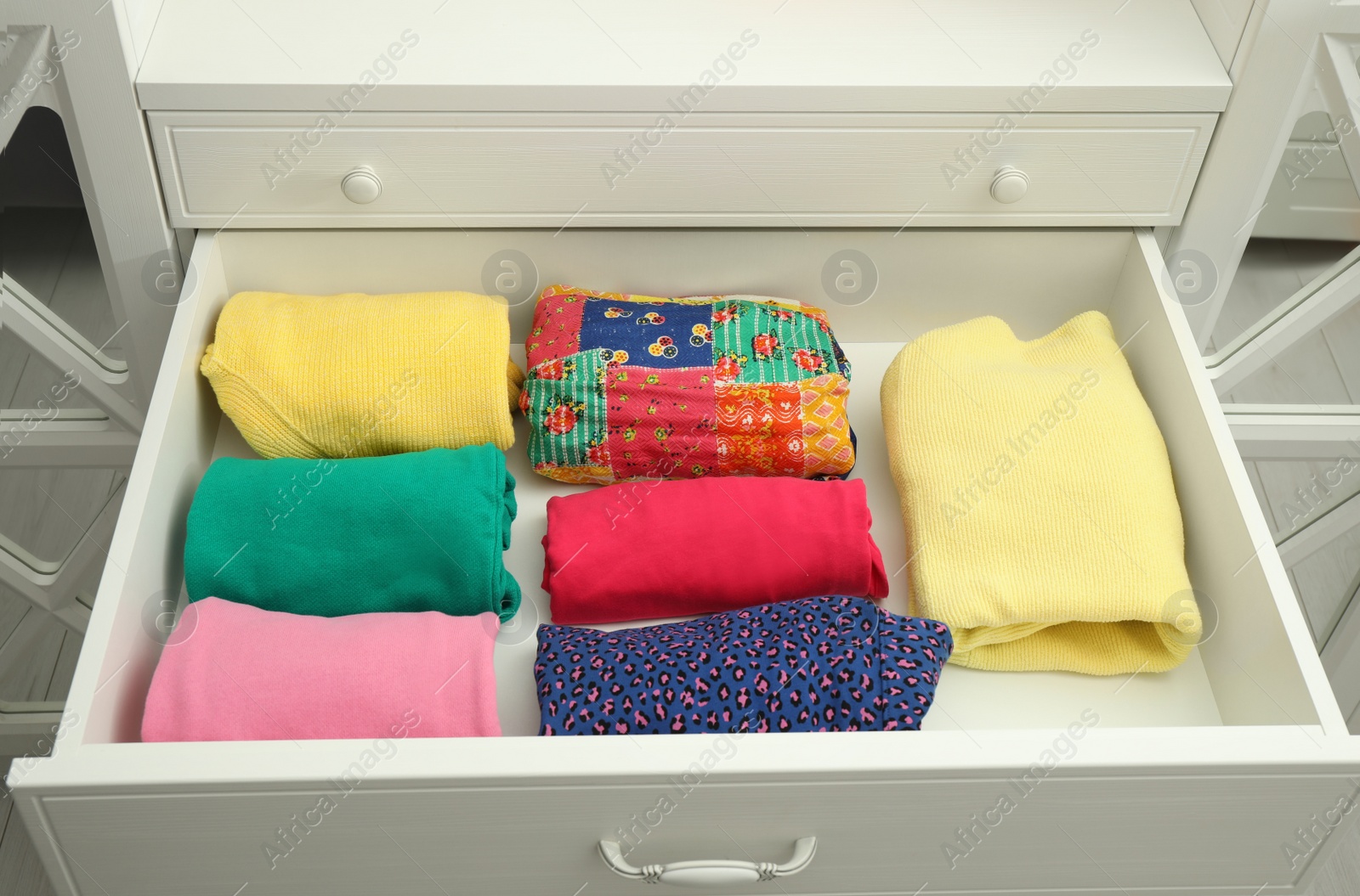 Photo of Folded clothes in open drawer. Apparel storage