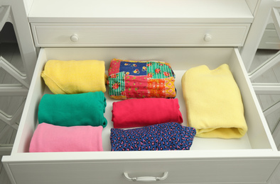 Photo of Folded clothes in open drawer. Apparel storage