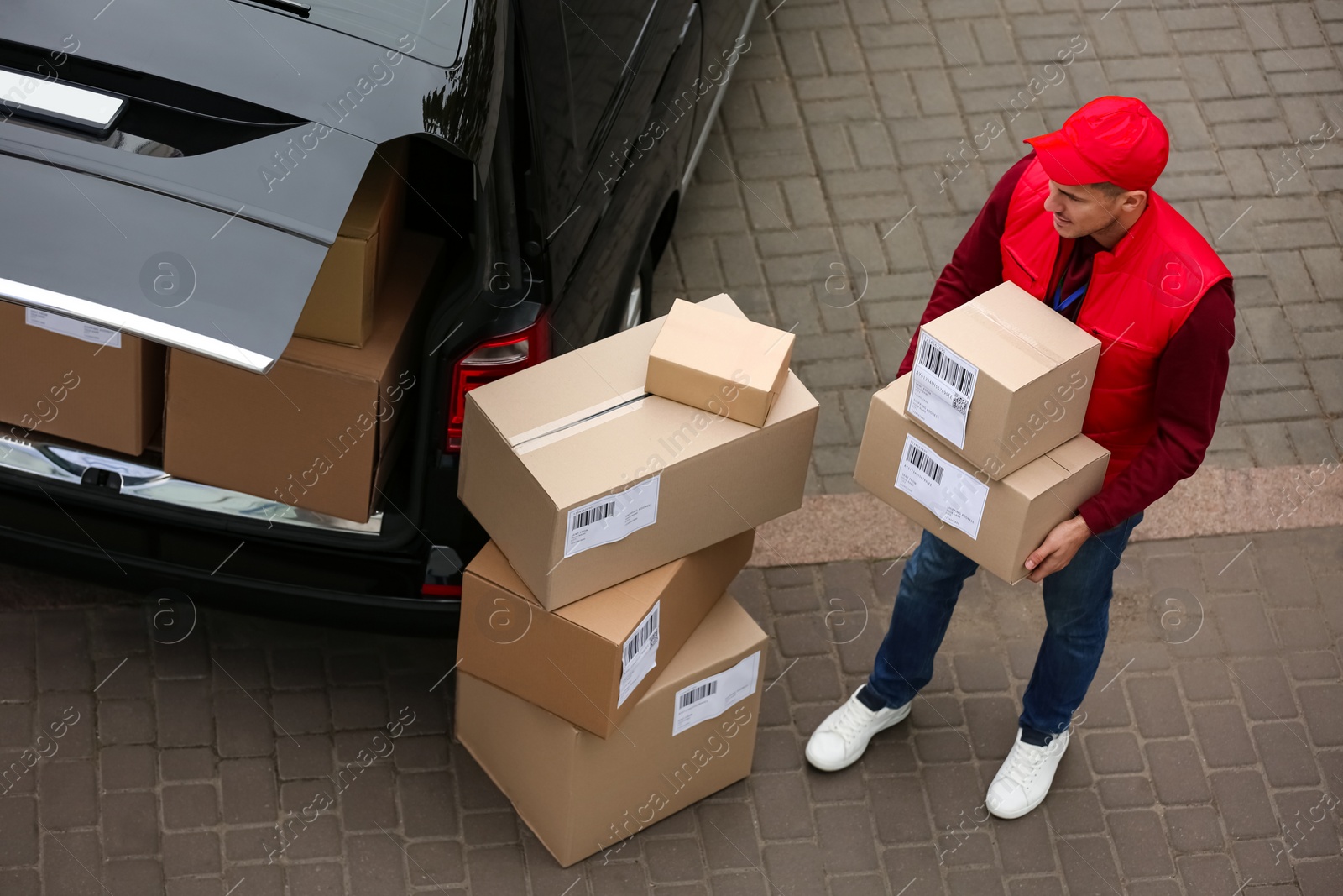 Photo of Courier with parcels near delivery van outdoors, above view