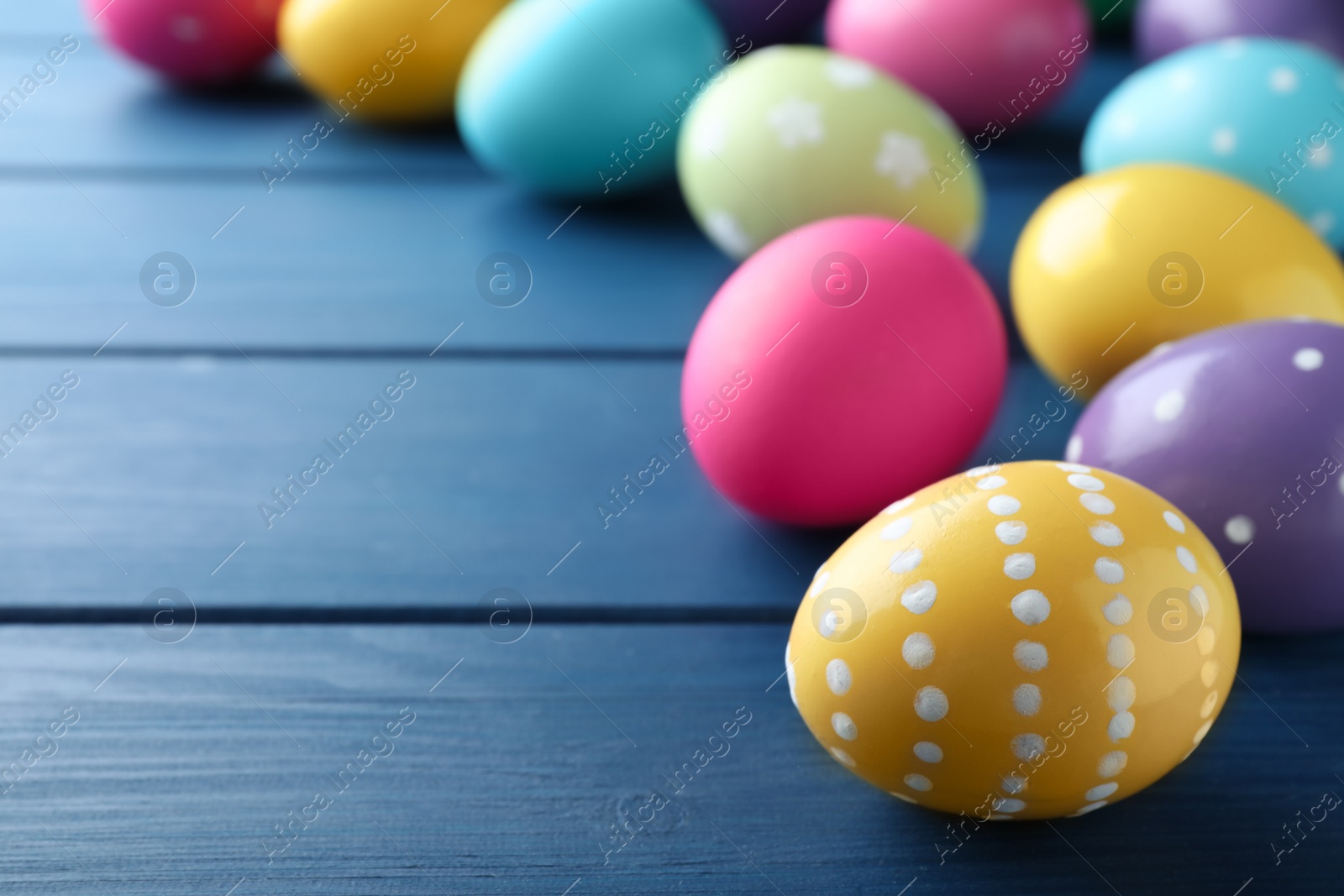 Photo of Colorful eggs on blue wooden background, closeup with space for text. Happy Easter