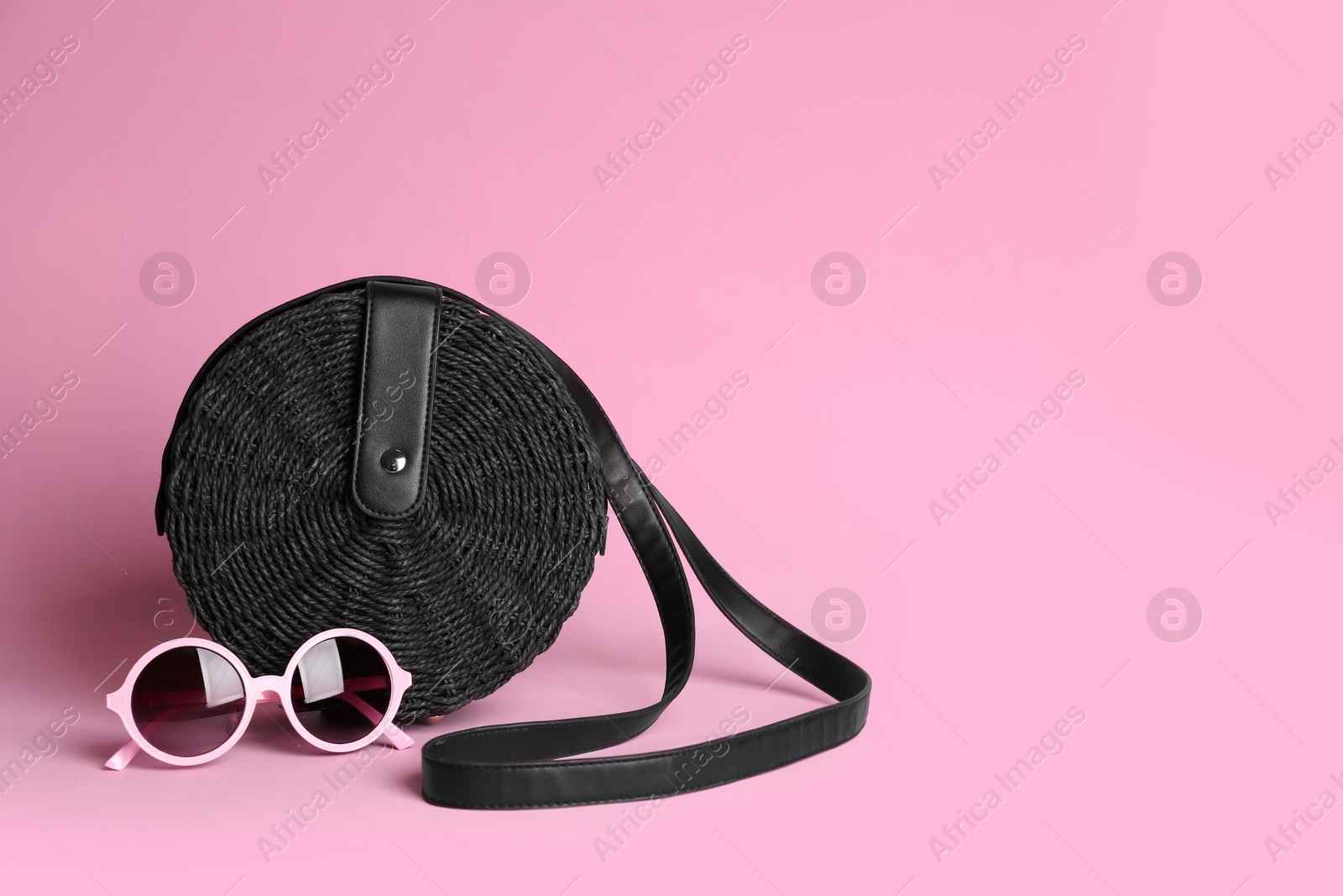 Photo of Stylish woman's bag and sunglasses on light pink background. Space for text