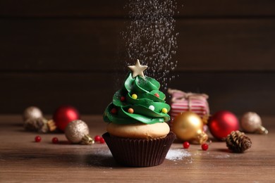 Sprinkling powdered sugar on Christmas tree shaped cupcake