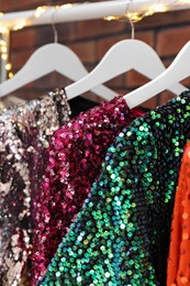 Collection of different beautiful women's party dresses on hangers, closeup. Stylish trendy clothes for high school prom