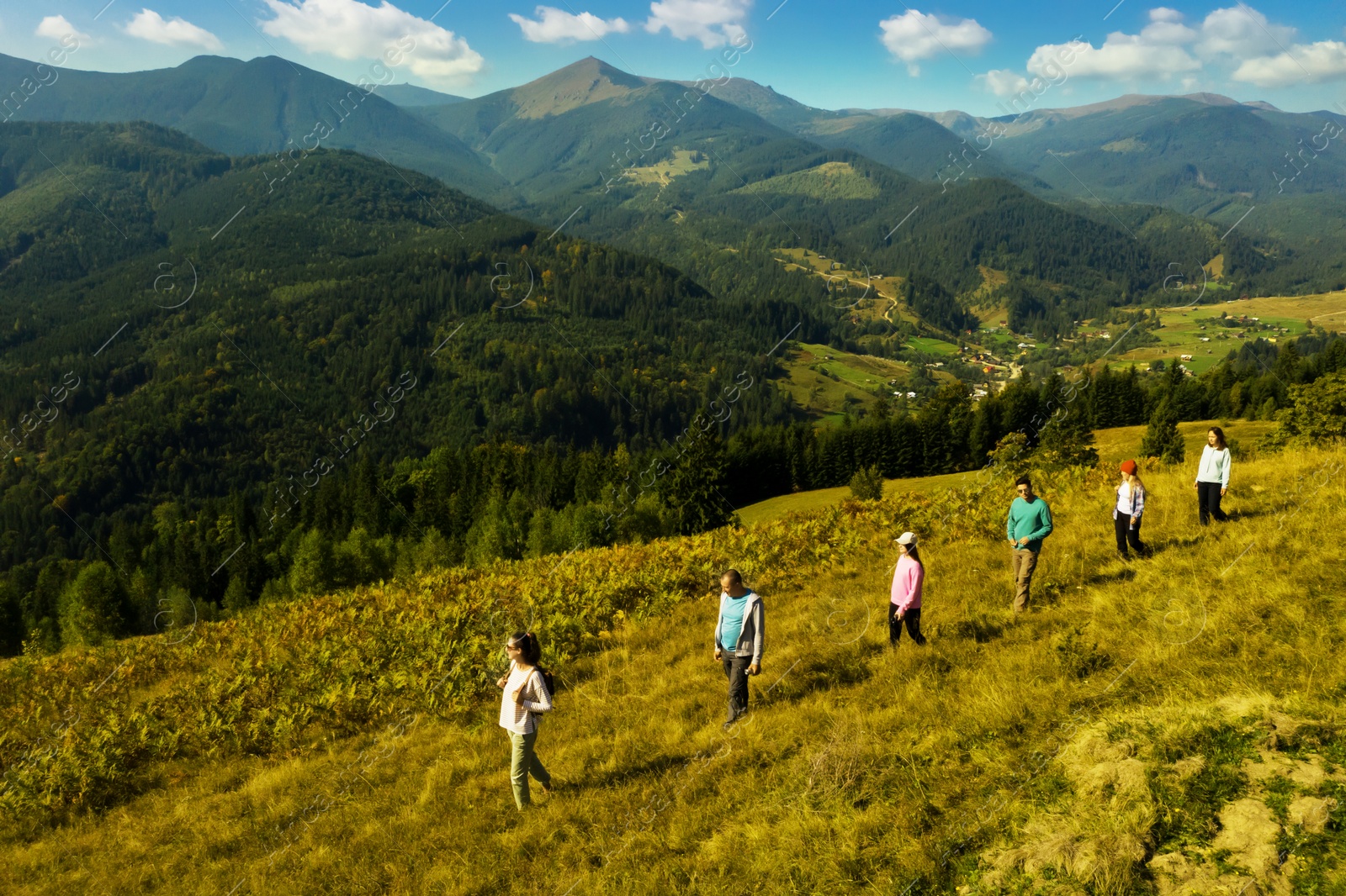 Image of Group of tourists walking on hill in mountains. Drone photography