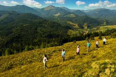 Image of Group of tourists walking on hill in mountains. Drone photography