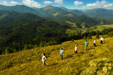 Group of tourists walking on hill in mountains. Drone photography