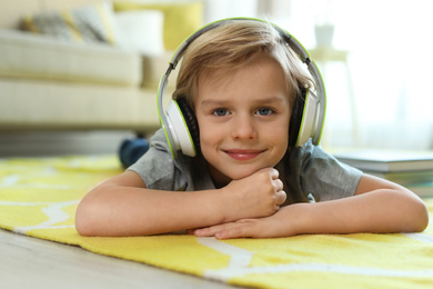 Photo of Cute little boy with headphones listening to audiobook at home