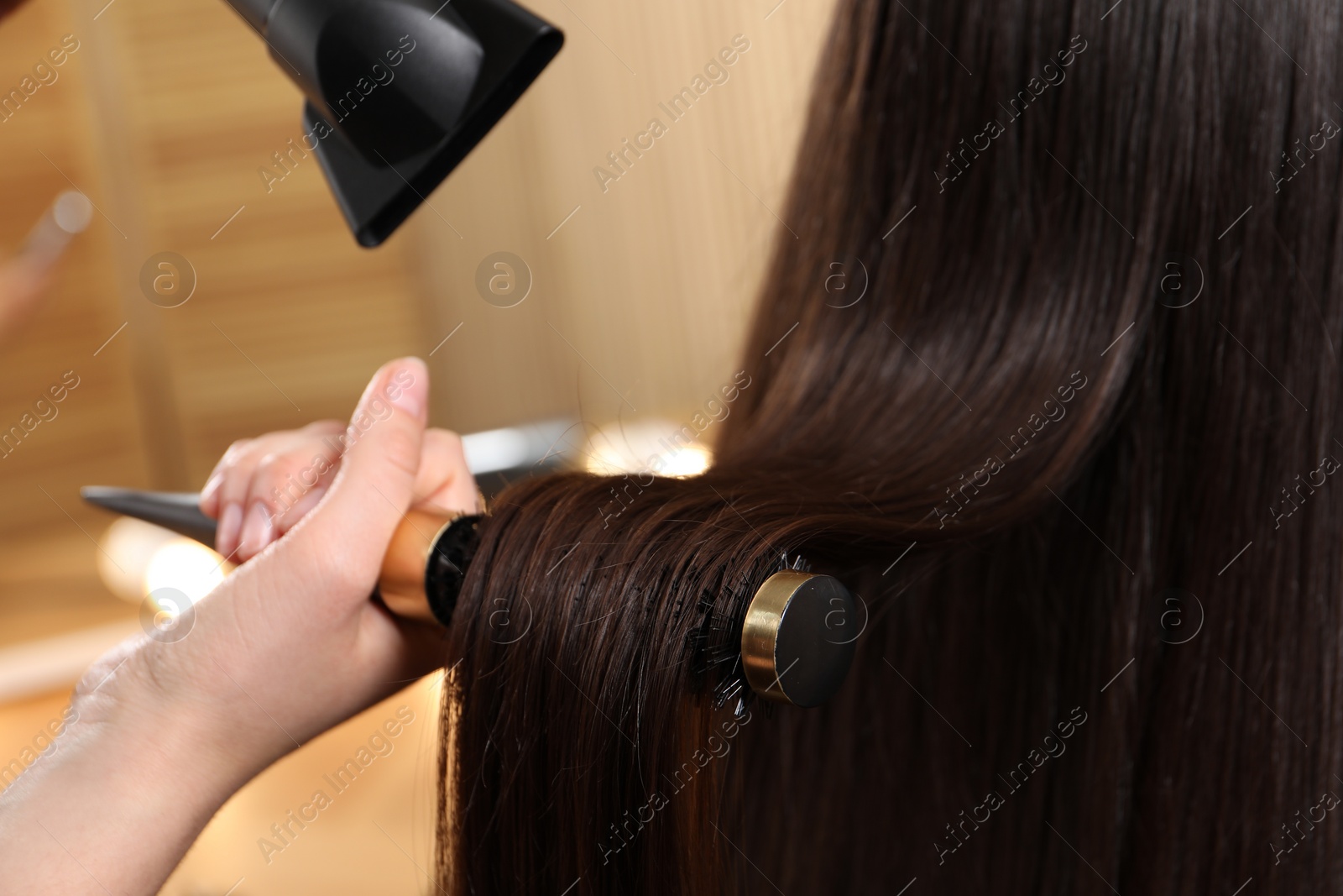 Photo of Hairdresser blow drying client's hair in salon, closeup