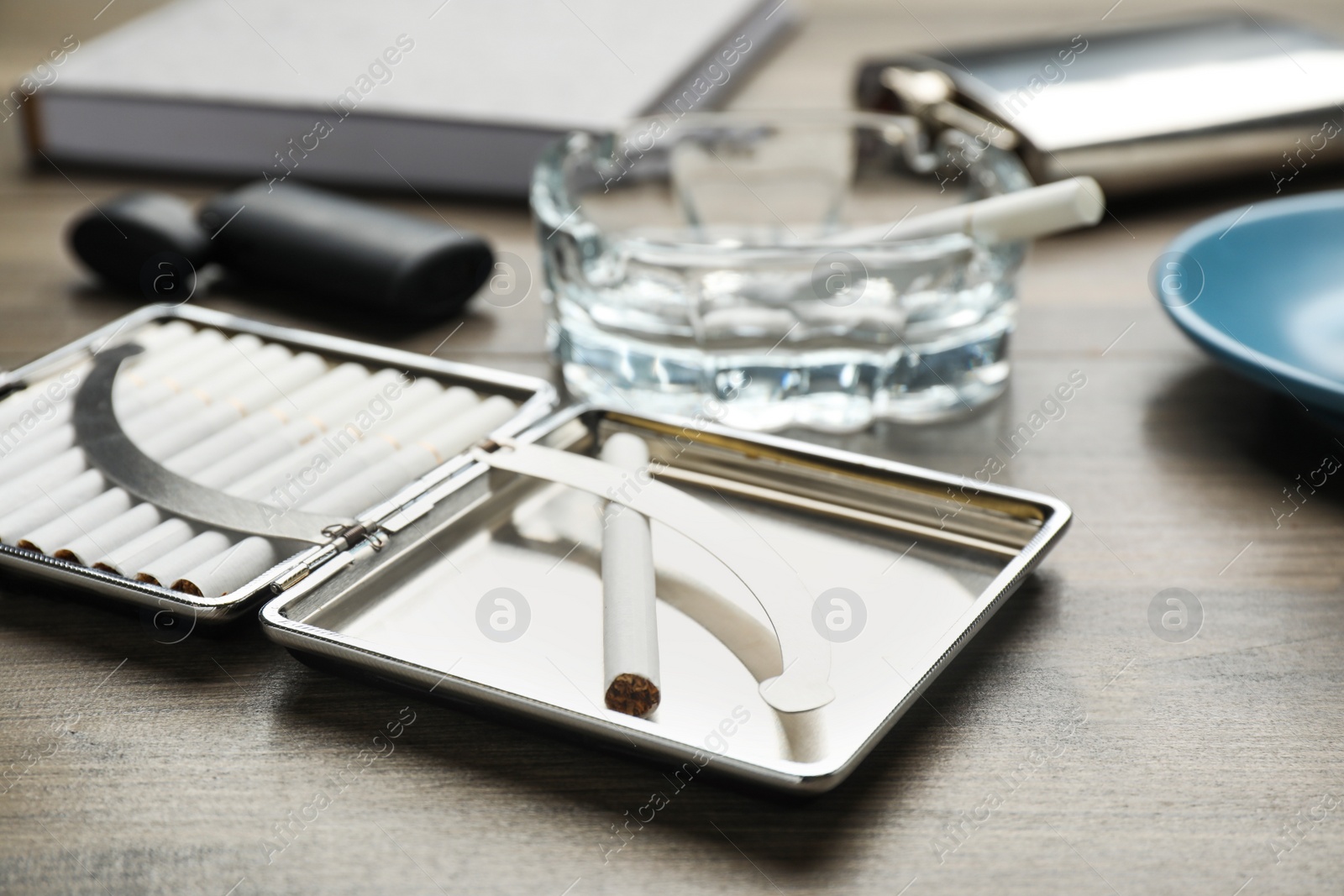 Photo of Silver case with tobacco filter cigarettes on wooden table, closeup