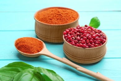 Photo of Bowls and spoon of red powdered pepper and corns on blue wooden table