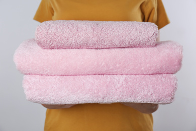 Photo of Woman holding fresh towels on light background, closeup