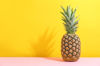 Photo of Fresh pineapple on table against color wall