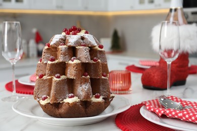 Photo of Delicious Pandoro Christmas tree cake decorated with powdered sugar and berries on white marble table